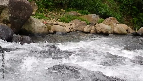 The flow of water flows fast in a clean river at the foot of Mount  photo