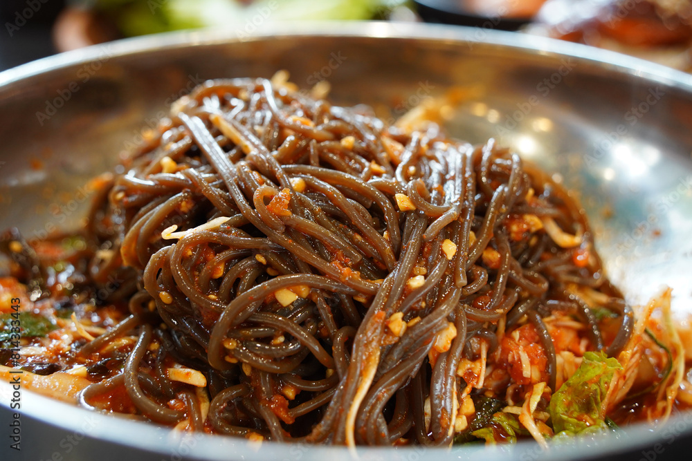 buckwheat noodles with spicy sauce on a stainless steel plate, close up