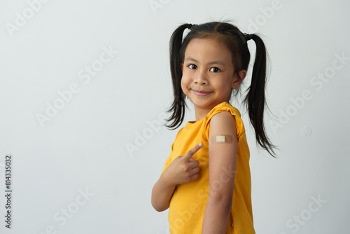 Little girl shows her arm after getting the vaccine, with a bandage on to protect against germs, first aid, treatment, medical concept, medicine and sanitation.