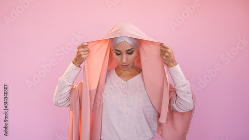 Hijab choice. Muslim female freedom. Unhappy sad woman covering head wearing headscarf traditional islamic clothing isolated on pink copy space background.