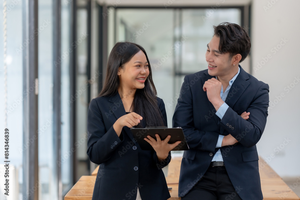Fototapeta premium Two engaged business professionals review and discuss documents in office.