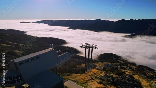Aerial fly over ski chairlift cable to reveal morning fog above the mountain forest at Thredbo, NSW, Australia photo