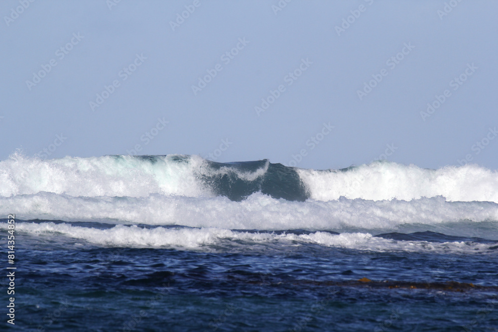 Fototapeta premium Close up of breaking ocean wave under a clear blue sky