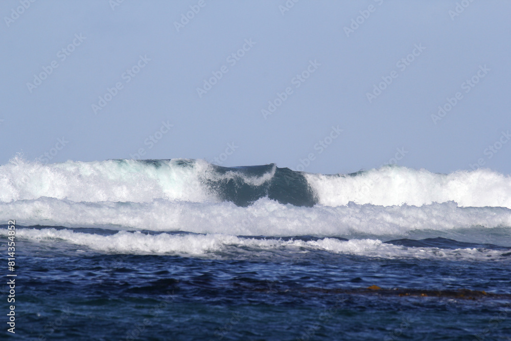 Close up of breaking ocean wave under a clear blue sky