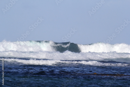 Close up of breaking ocean wave under a clear blue sky