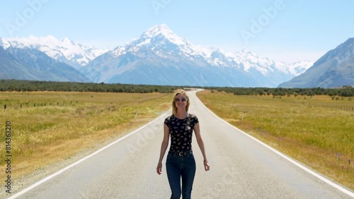 Lady with arms out stretched looking towards snow capped Mountain before turning photo