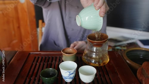 Midsection of man brewing herbal tea. Male wearing casuals preparing hot beverage on wooden table. He is having chhinese drink at home.