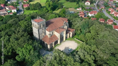 orbital flight with drone over the church of San Vicente 16th-17th centuries in Rio Frio Cantabria located at the top of a hill populated with oaks we see its magnificent bell tower Spain photo