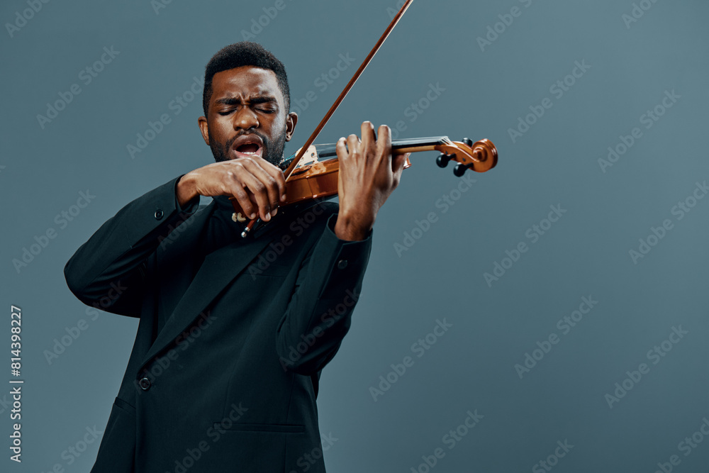 African American musician in a suit playing the violin on a gray background in a dramatic and elegant performance concept African American musician in a suit playing the violin on a gray background in a dramatic and elegant performance concept