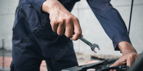 Mechanic using wrench while working on car engine outside the service center   Repair and service.
