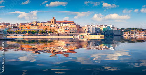Colorful buildings of coastal town Otranto reflected in the calm waters of Adriatic sea. Sunny morning cityscape of Otranto town, Apulia region, Italy, Europe. Splendid spring view of Alimini Beach.