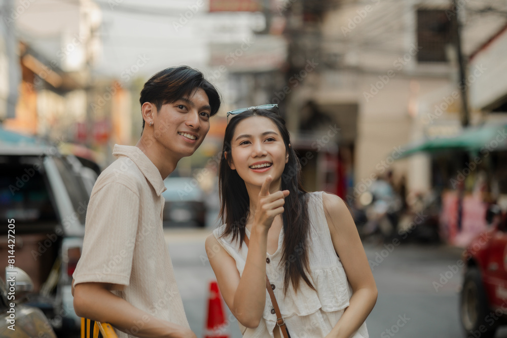 Fototapeta premium the young lovely couple is walking around traditional food market under the sun, love is showing from their face when they have conversation because they love each other, dating