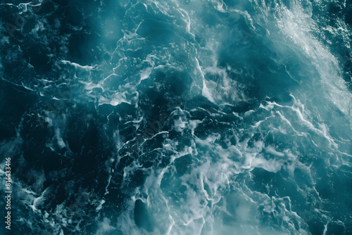 Dynamic photo of the sea's turbulent textures in shades of teal and dark blue, showcasing the chaotic energy of ocean waves