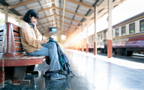 Young hipster female traveler using digital tablet  at train station before travel.