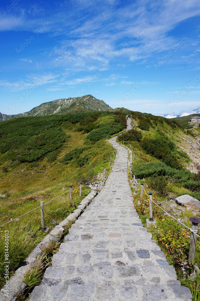 よく晴れた青空と立山の風景と石畳の遊歩道