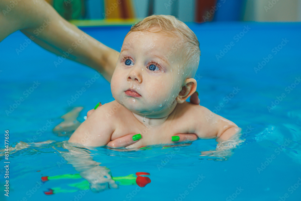 Swimming pool for babies. A little 8-month-old boy is learning to swim in the pool with a coach. Swimming pool for babies. A little 8-month-old boy is learning to swim in the pool with a coach.