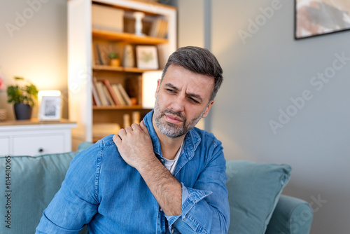 Young man with shoulder pain. male holding his painful shoulder. man hand holding his shoulder suffering from shoulder pain suffering from pain in hand at home.