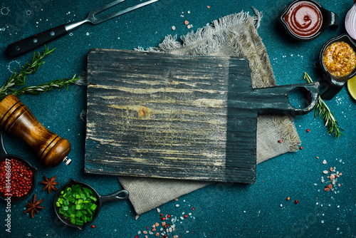 Kitchen cutting board on table with spices, vegetables and herbs. Free space for a recipe. Rustic style. On a dark background. © Yaruniv-Studio