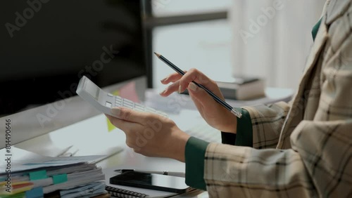 a female accountant is using calculator, head of marketing department is planning to analysis about investment in currency, calculating to pay yearly tax, find the total of the company's expenses photo