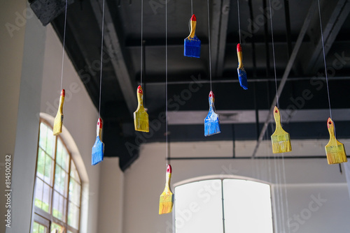 The paint brushes are suspended from the ceiling.  photo