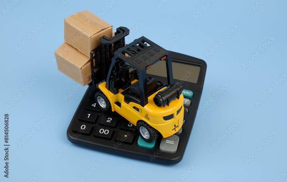 Top view of forklift truck carrying carton boxes on black calculator on blue background.