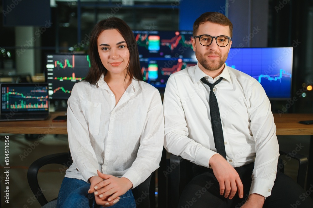 Fototapeta premium Team of stockbrokers are having a conversation in a dark office with display screens