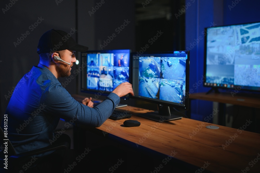 Security operator controls CCTV cameras in office at night. Modern security system and social safety concept Security operator controls CCTV cameras in office at night. Modern security system and social safety concept