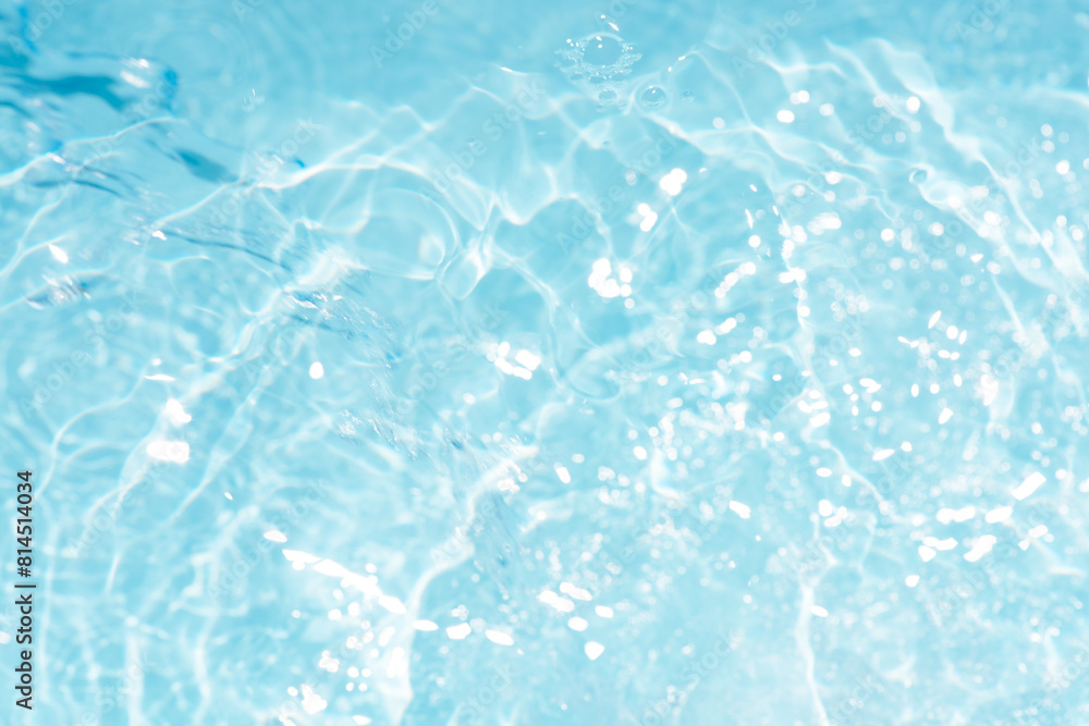 Obraz premium Blue water with ripples on the surface. Defocus blurred transparent blue colored clear calm water surface texture with splashes and bubbles. Water waves with shining pattern texture background.