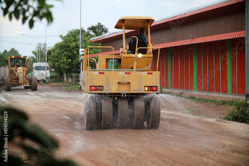 Obraz na plátně A road roller is spraying water onto the road in the upper stages to increase soil compactness in building a sustainable road