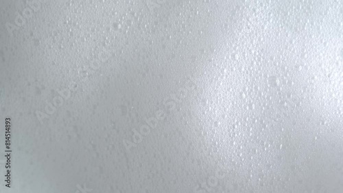 Soap bubbles on window glass. Macro shot of white soap suds flowing down of glass. Shower concept. Cleaning windows, hygiene, disinfection, housework, household, cleanup, washing. photo