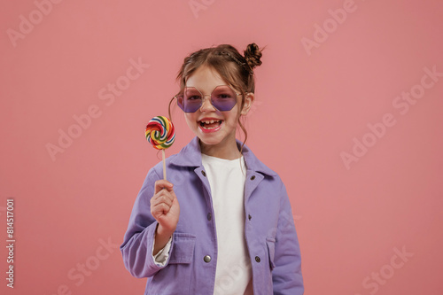 Delicious candy. Cute little girl is against pink background © standret
