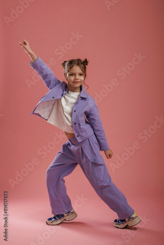 Dancing, having fun. Cute little girl is against pink background © standret