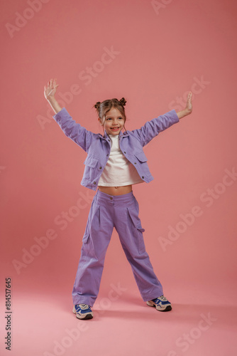 Dancing, having fun. Cute little girl is against pink background © standret