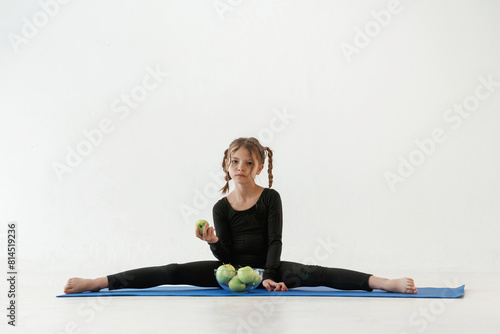 Healthy eating, green apples. Little girl in yoga clothes is on the fitness mat © standret
