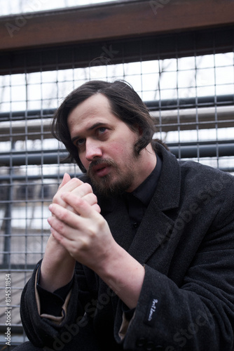 a serious man in a black coat on the street in Krasnoyarsk