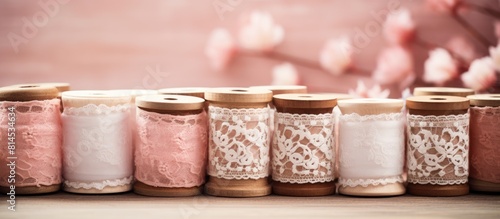 Wooden spools wrapped with vintage cotton lace trims in pretty pink and beige colors creating a nostalgic copy space image