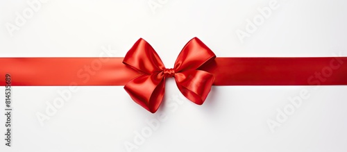 A shiny red silk ribbon on a white background creating a festive atmosphere The image is taken from a top down perspective It is a copy space image
