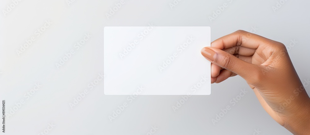 Obraz premium A white prepaid card is held by a woman s hand against a white background with ample empty space for additional images or text