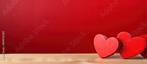 A copy space image with two wooden hearts placed on a vibrant red background symbolizes the essence of Valentine s Day and celebrates love between all couples photo