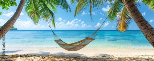 Serene beach scene with a hammock hanging between palms, overlooking the clear ocean and blue sky, ideal for relaxation photo