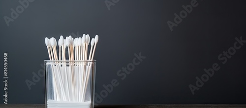Top view of a grey background with a plastic container and cotton swabs There is copy space available for text photo