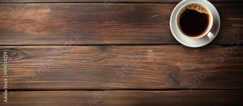 Top down view of a cup of fragrant coffee resting on a rustic wooden table with ample room for text in the background