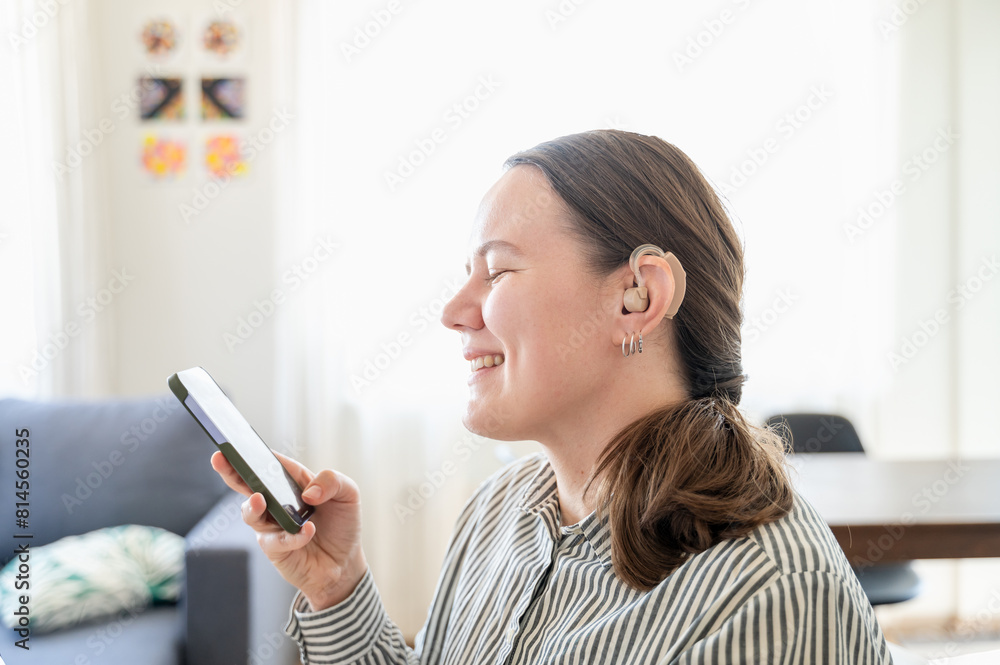 Woman with hearing aid using smartphone and smiling Woman with hearing aid using smartphone and smiling