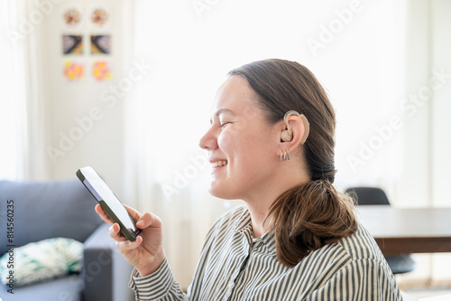 Woman with hearing aid using smartphone and smiling