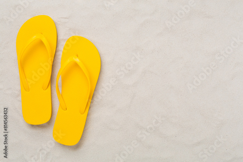 Bright flip-flops on sand background, top view. Summer concept