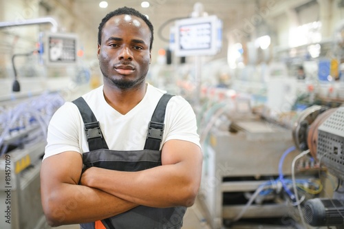 African male engineer. Control a material production machine system, working in a plastic and steel industry regarding the company's product business.