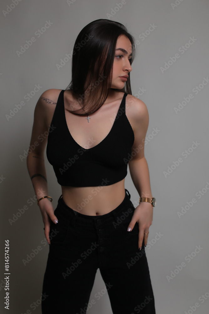 Portrait of a beautiful fashion model in the studio on a light background, wearing a black short clothes and trousers, barefoot Portrait of a beautiful fashion model in the studio on a light background, wearing a black short clothes and trousers, barefoot