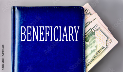 BENEFICIARY - word on a blue book on a gray background with banknotes photo