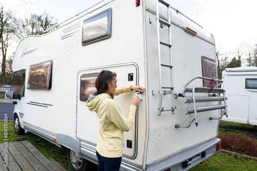 Woman opening a compartment of a motorhome from the outside