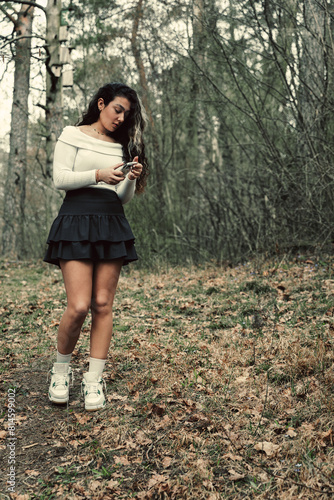 A teenage girl takes pictures in a spring forest on a smartphone.